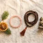 mindful-christmas-gift-flatlay-crystal-mala-buddha Flatlay of a rose quartz bracelet, sandalwood mala beads, and a small Buddha pendant styled as Christmas gifts under $50