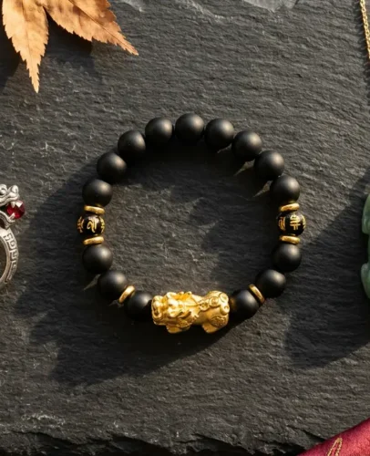 Pixiu ring, bracelet, and pendant displayed side by side on dark slate, comparing three feng shui wealth forms
