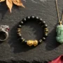 pixiu-ring-vs-bracelet-vs-pendant-comparison Pixiu ring, bracelet, and pendant displayed side by side on dark slate, comparing three feng shui wealth forms