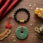 Zenginlik ve şans için feng shui hediyelerinin düz bir şekilde sergilendiği fotoğraf: bir Pixiu bileklik, sitrin taşı, kırmızı ipe dizilmiş feng shui paraları, bir yeşim kolye ve bir para kurbağası.