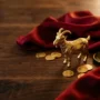ohnivá-koza-2027-feng-šuej-hrdina Zlatá figurka kozy s červeným hedvábím a zlatými mincemi, symbolizující rok feng shui Ohnivé kozy 2027.