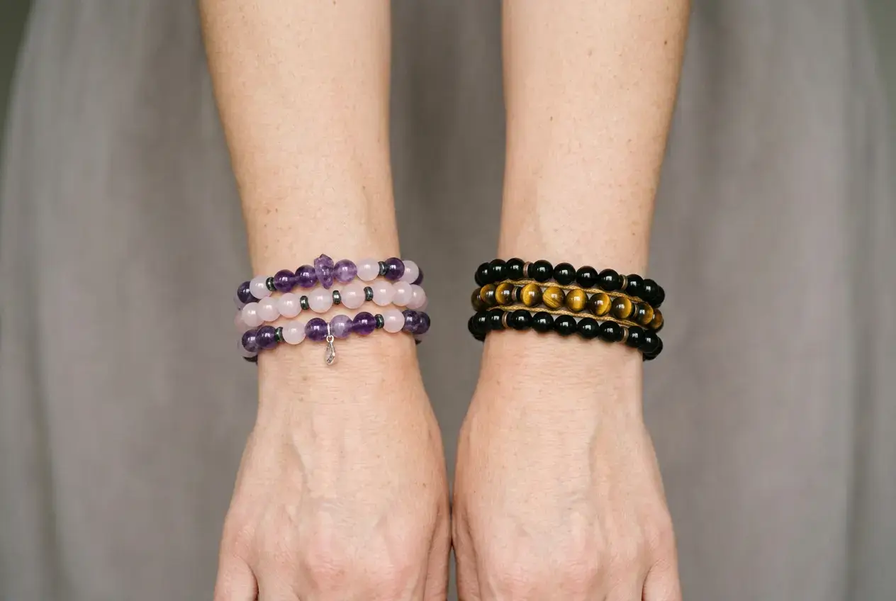 Two forearms showing calming crystal bracelets on the left wrist and protective stones on the right wrist.