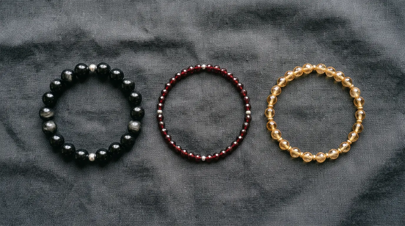 Black obsidian, red garnet and golden topaz bracelets arranged side by side to compare Scorpio season crystals