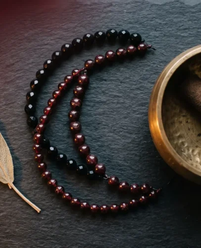 scorpio-season-2026-transformation-hero Black obsidian and garnet jewelry beside a crescent moon, symbolizing Scorpio season 2026 transformation