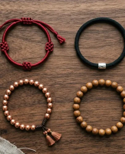 tibetan-bracelet-types-comparison.webp Four Tibetan bracelet styles laid flat: red knotted cord, mantra bracelet, copper bead bracelet and 21-bead wrist mala