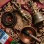 tibetan-ritual-objects-flatlay Vajra, bell, mala beads, and a singing bowl arranged on a maroon cloth, a complete set of Tibetan Buddhist ritual objects