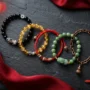 best-feng-shui-bracelets-2027-five-picks.jpg Five feng shui bracelets for wealth, good luck and health arranged on dark slate with red silk
