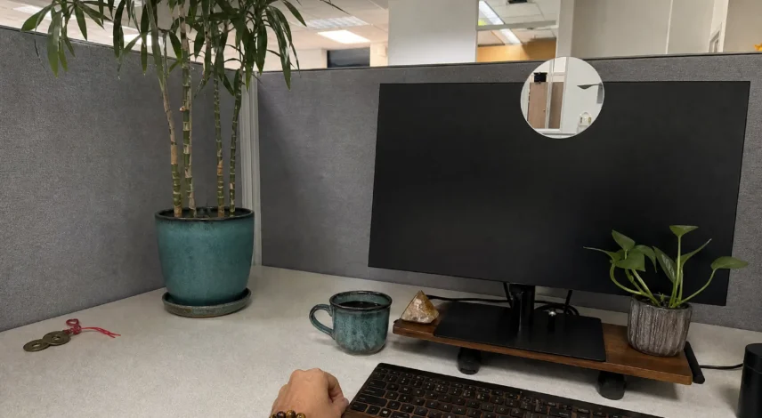 cubicle-feng-shui-2027-mirror-plant-wealth-corner Cubicle desk with a small mirror on the monitor, a tall plant on the desk corner, and a three-coin set in the back-left corner