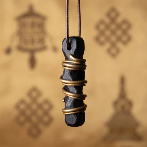 Black ebony wood pendant with a drilled hole, threaded on a brown wax cord and wrapped in brass wire