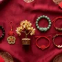 feng-shui-gifts-chinese-new-year-2027-ranked.jpg ثماني هدايا فنغ شوي للعام الصيني الجديد 2027 على حرير أحمر، تشمل سوار بيكسيو، وعملات معدنية لجلب الحظ، وشجرة نقود من حجر السترين
