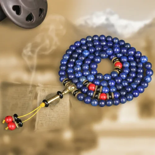 Flat lay of 108 lapis lazuli prayer beads with red turquoise, black agate spacers and yellow tassel beside incense smoke