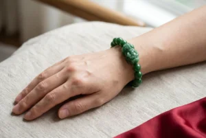 Hands presenting a red gift box with a green jade Pixiu bracelet and handwritten card for Lunar New Year