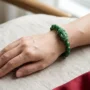 wear-pixiu-bracelet-left-wrist-head-outward.jpg Hands presenting a red gift box with a green jade Pixiu bracelet and handwritten card for Lunar New Year